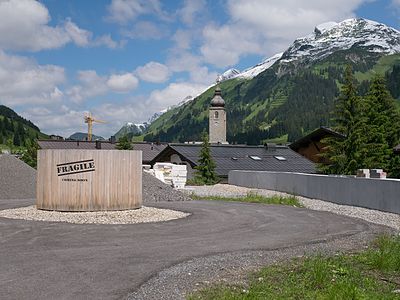 Back side of a hotel construction site in Lech, Vorarlberg, Austria. Views of landscape and church tower.