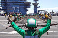 Defense.gov News Photo 110702-N-AW206-007 - U.S. Navy Petty Officer 3rd Class Ashley Pryor signals for sailors to set up the aircraft barricade during a barricade drill aboard the aircraft.jpg
